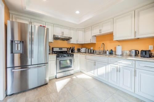cocina con armarios blancos y nevera de acero inoxidable en @ Marbella Lane - Cozy & Bright Duplex in W Covina, en West Covina