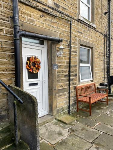 een deur naar een bakstenen gebouw met een bank ernaast bij Brook Cottage in Holmfirth