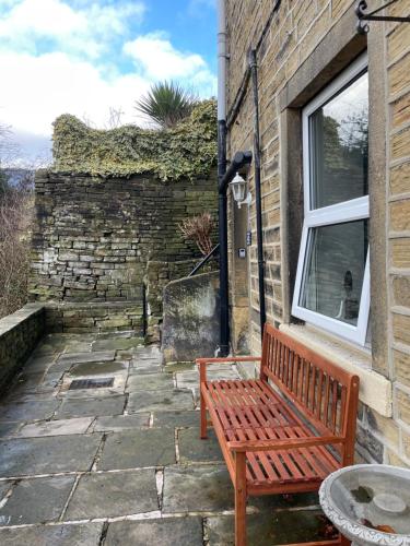 a wooden bench sitting outside of a building at Brook Cottage in Holmfirth