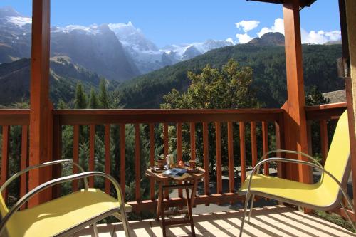 a porch with two chairs and a table and mountains at Panoramic Village - Locations vue Glaciers - Chez Philippe in La Grave