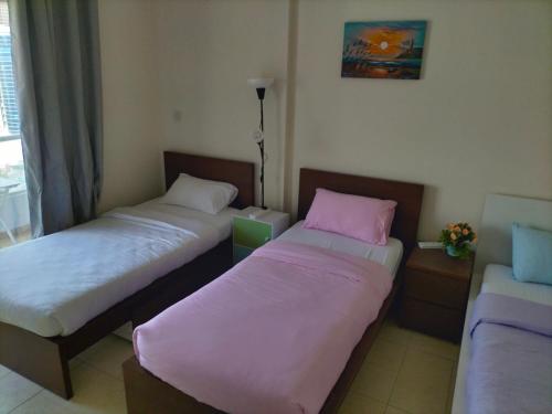 two beds in a room with pink sheets at Amazing apartment 2 bed rooms in Tecom 6 pax in Dubai