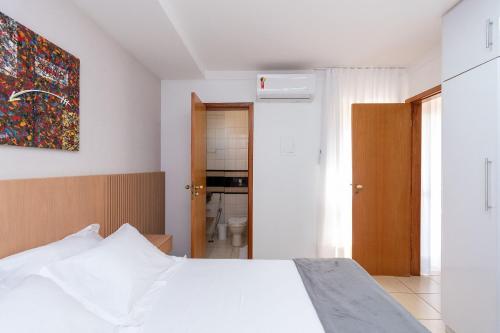 a bedroom with a white bed and a bathroom at Tranquilidade e Conforto no Setor Leste Universitário in Goiânia