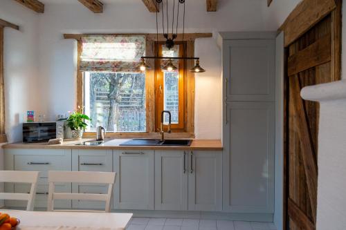 a kitchen with white cabinets and a sink and a window at Casele cu Stuf B&B Haus Ulrike in Sălicea