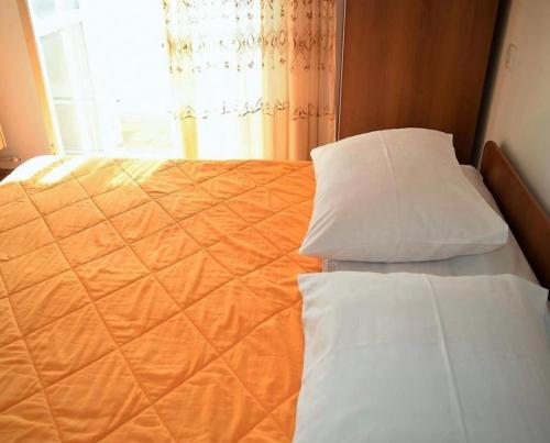 an orange bed with two pillows and a window at Room Eufemija-Rab in Rab
