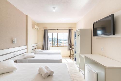 a hotel room with two beds and a flat screen tv at Hotel Conexão in Penha