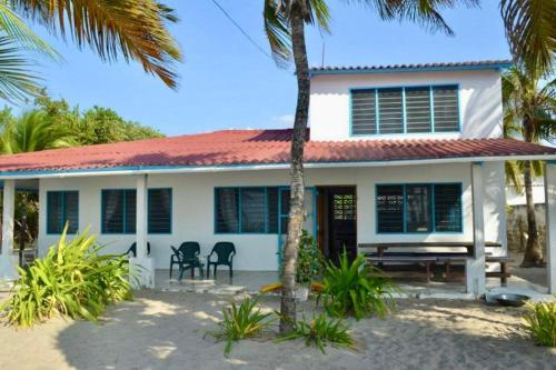 a white house with a palm tree in front of it at Casa Manglar in Tolú