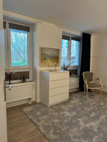 - un salon avec une commode et 2 fenêtres dans l'établissement Am kleinen Mühlenteich - Zentrale ruhige Lage mit Parkplatz und Fahrrädern, à Flensbourg