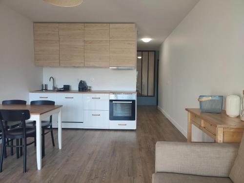 una cocina con armarios blancos y una mesa con sillas. en L'Appart de Villard en Villard-de-Lans