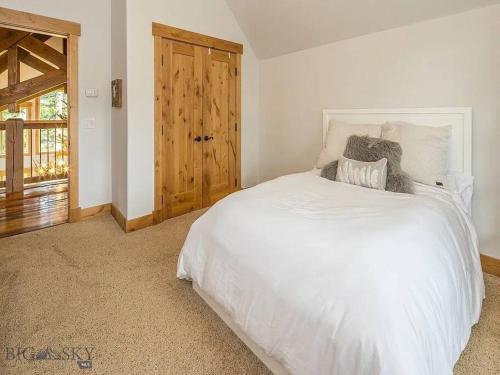 a bedroom with a white bed and a wooden door at Luxury Mountain Retreat in Big Sky