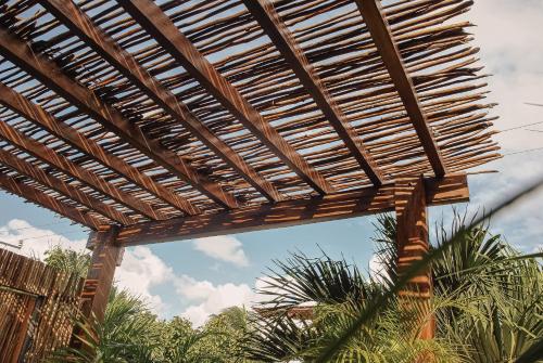 a wooden pergola with palm trees in the background at Boutique Hotel Posada 06 Tulum in Tulum