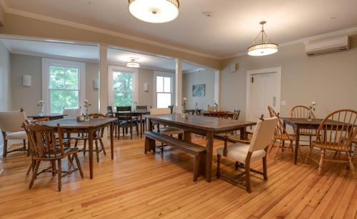 uma grande sala de jantar com mesas e cadeiras de madeira em Lakehouse Inn em Lee