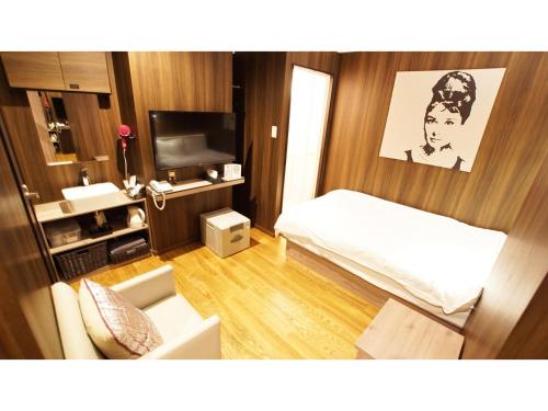 um pequeno quarto com uma cama e uma televisão em hotel mio omiya - Vacation STAY 64001v em Saitama