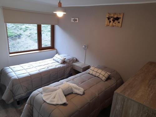 a room with two beds and a table and a window at Del Sendero Caviahue in Caviahue
