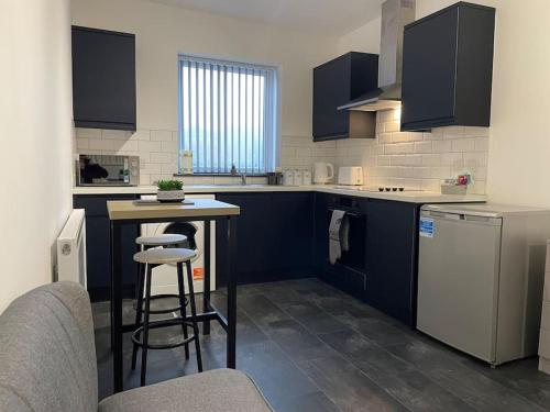 a kitchen with blue cabinets and a table and stools at Modern Apartment With En-suite & Private Kitchen in Stoke on Trent