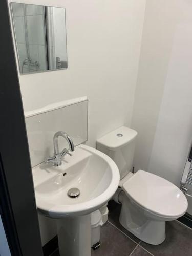 a white bathroom with a toilet and a sink at Modern Apartment With En-suite & Private Kitchen in Stoke on Trent