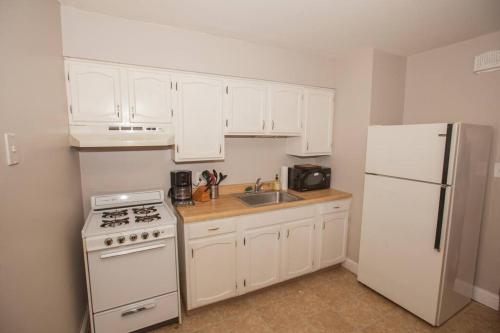 a kitchen with white cabinets and a white refrigerator at Hip & Cozy to Explore the City or Catch a Game in Pittsburgh