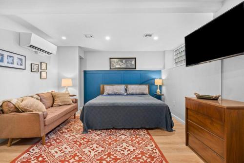 a bedroom with a bed and a couch and a flat screen tv at Trendy & Hip South Side Studio Walk to Downtown in Pittsburgh