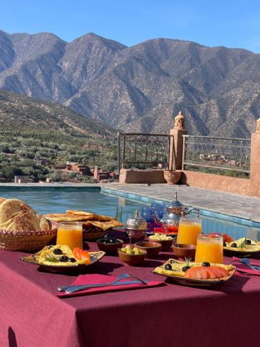 a table with food on it next to a pool at KASBAH LA DAME BIJA in Tassa Ouirgane