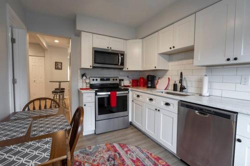 a kitchen with white cabinets and a table and a dining room at Urban Oasis Easy City Access Brand New in Pittsburgh