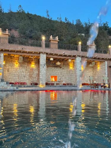 a building with a fountain in the water at night at KASBAH LA DAME BIJA in Tassa Ouirgane