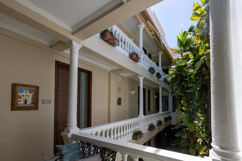 a balcony of a house with white columns and plants at Hotel Casa La Fe in Cartagena de Indias