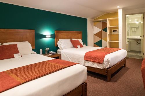 duas camas num quarto de hotel com paredes verdes em Maytaq Wasin Boutique Hotel em Cusco