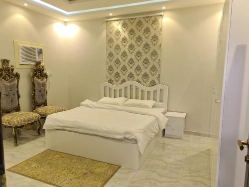 a white bedroom with a bed and a chair at فيلا ميسرة الهدا in Al Hada