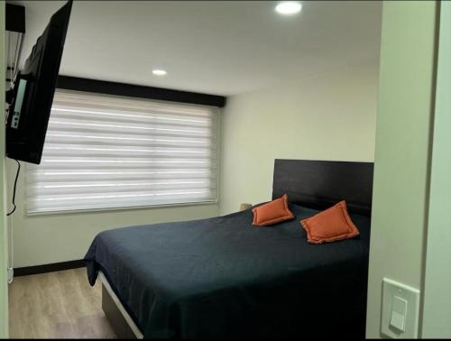 - une chambre dotée d'un lit avec deux oreillers orange et d'une télévision dans l'établissement Departamento Sector de la Embajada Americana, à Quito