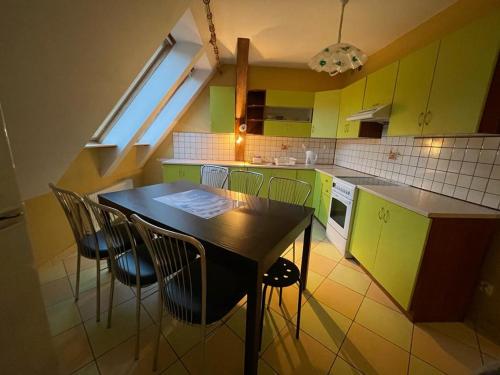 eine Küche mit grünen Schränken sowie einem Tisch und Stühlen in der Unterkunft Apartament pod Stożkiem in Sokołowsko