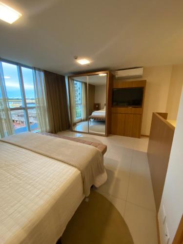 a hotel room with a bed and a television at Flat Jade Hotel Brasília in Brasilia