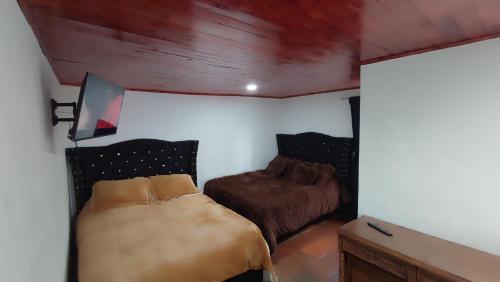 a bedroom with two beds in a room with wood ceilings at Cabañas Casa Campo Guatavita in Guatavita