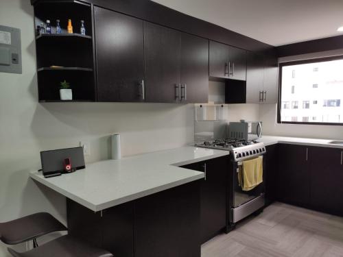 uma cozinha com armários a preto e branco e um fogão em Departamento Sector de la Embajada Americana em Quito