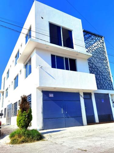 a white house with blue garage doors in front of it at Habitaciones Mimado morelia in Morelia