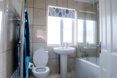 baño con aseo y lavabo y ventana en Newport house sleeps 5 near Junction 27 on M4, en Newport