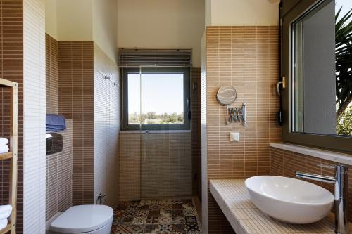 a bathroom with a sink and a toilet and a window at Rizes Villa with Jazuzzi & Heated Pool in Agia Triada
