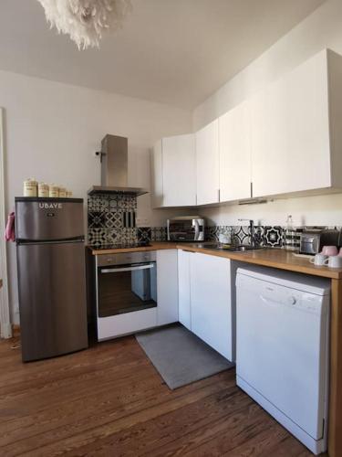 une cuisine avec des armoires blanches et des appareils en acier inoxydable dans l'établissement La marmotte, à Barcelonnette