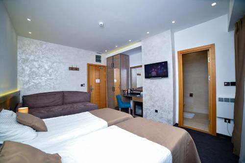 ズラティボールにあるApartman Milinović Zlatibor - Hotel Alibiのベッド2台とソファが備わるホテルルームです。