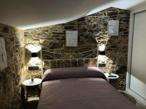 een slaapkamer met een bed en een stenen muur bij A Caseta in A Coruña