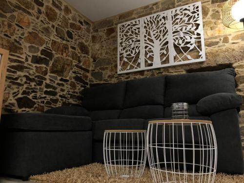a living room with a black couch and a stone wall at A Caseta, en plena Costa da Morte in A Coruña