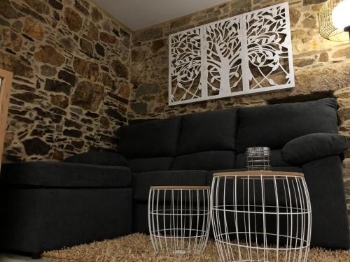 a living room with a black couch and a stone wall at A Caseta in A Coruña
