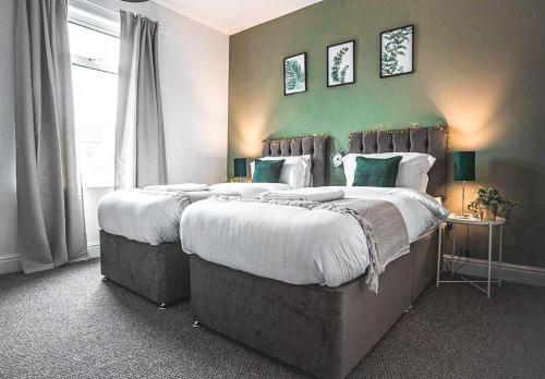 a bedroom with two beds and a green wall at DIGS Cosy stay Coventry City Centre sleeps5 with FREE parking in Coventry