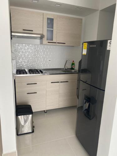 een keuken met een zwarte koelkast en houten kasten bij Apartamento Cerca al mar in Cartagena