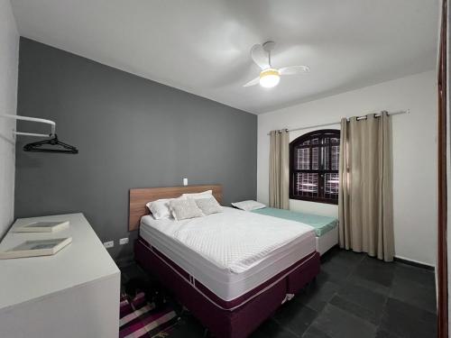 um quarto com uma cama, uma secretária e uma janela em AeK Locações Casa Praia em Peruíbe