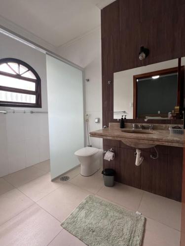 a bathroom with a toilet and a sink and a mirror at AeK Locações Casa Praia in Peruíbe