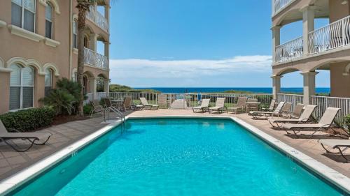 a swimming pool next to a building with chairs at Monterey Condos C301 in Seacrest