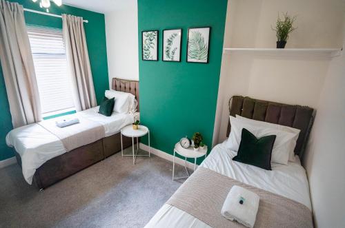 Habitación con 2 camas y pared verde. en Comfortable equipped House in Nuneaton sleeps5 with FREE parking, en Nuneaton