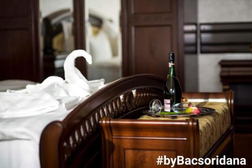 Hotel Bacsoridana في Tecuci: زجاجة من الشمبانيا وصحن من الفواكه على السرير