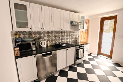 a kitchen with white cabinets and a checkered floor at Rezydencja Nosal in Zakopane