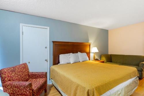 a hotel room with a bed and a chair at Rodeway Inn Colonial Heights I-95 in Colonial Heights
