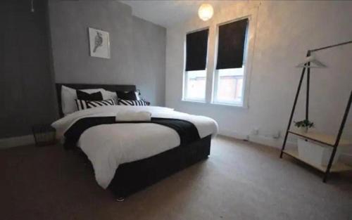 a bedroom with a black and white bed and a window at CONTRACTORDIGS with FREE parking - excellent road links in Nuneaton